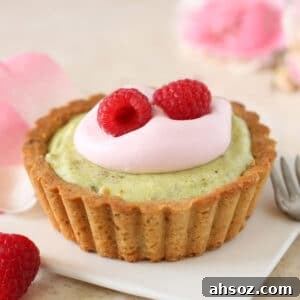 A pistachio rose tart on a white square dessert plate